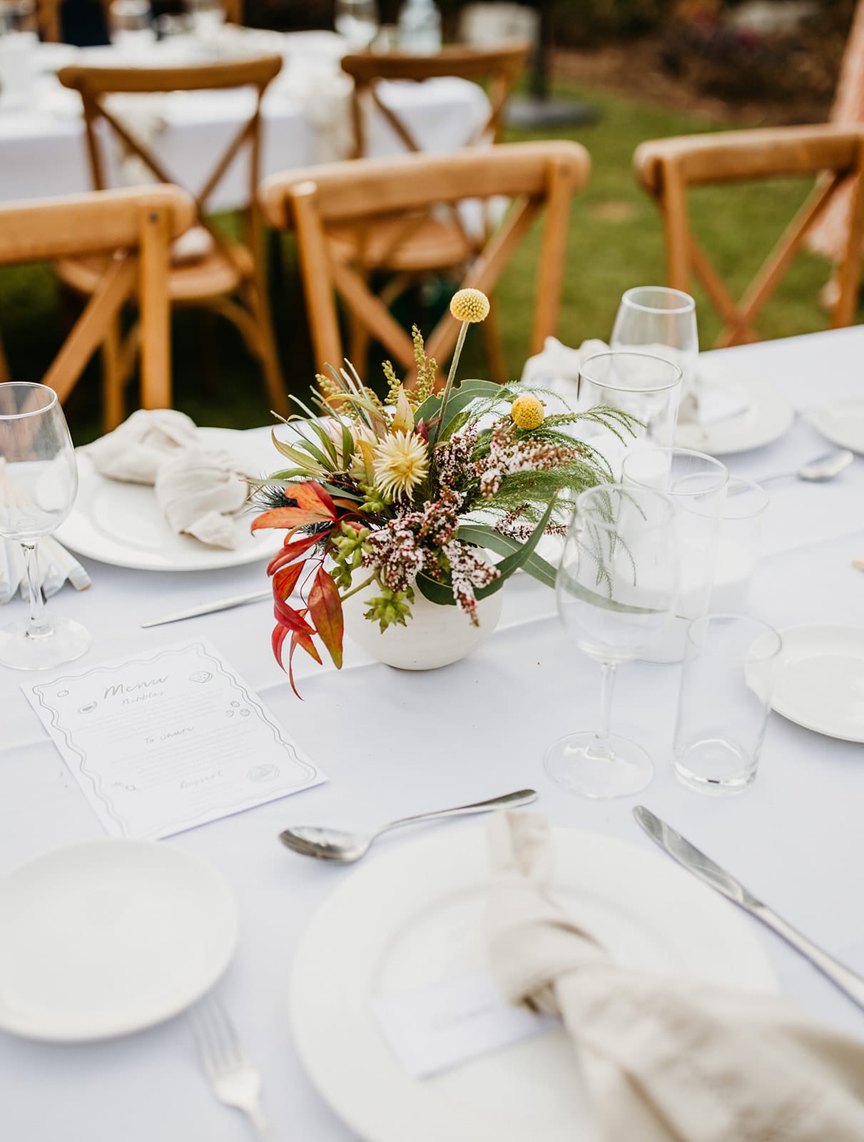 Decorated outdoor wedding table with floral centerpiece of native blooms