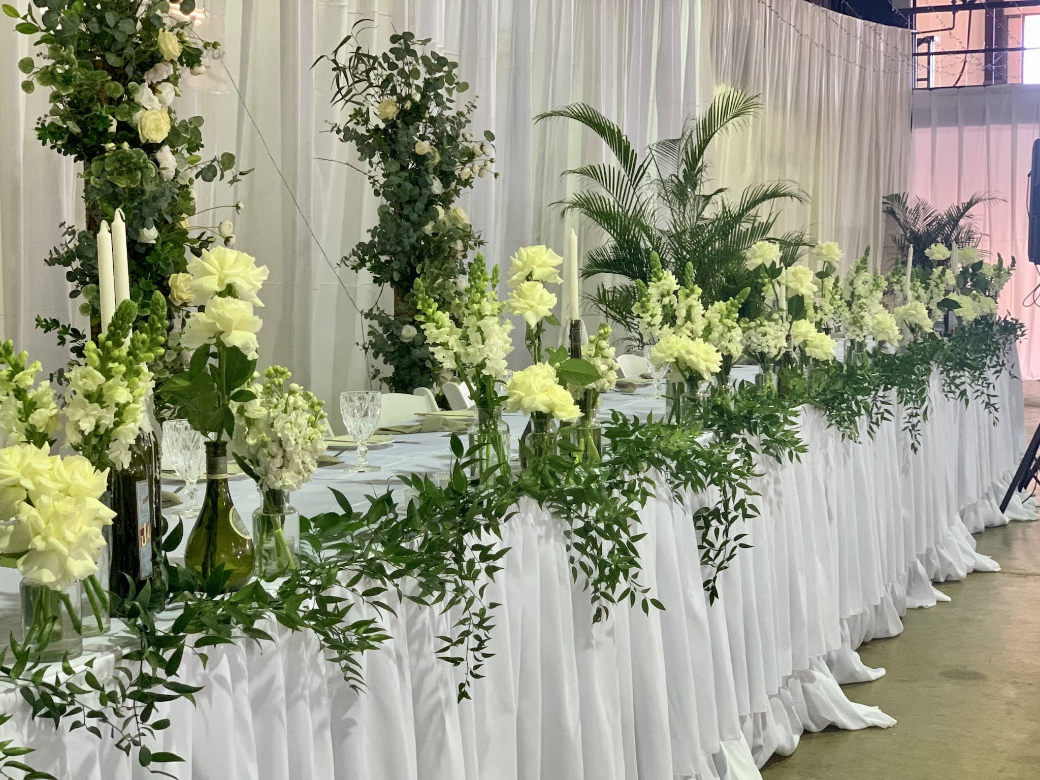 Bridal table flowers clusters of wine bottles with white flowers - Beija Flor Darwin Florist