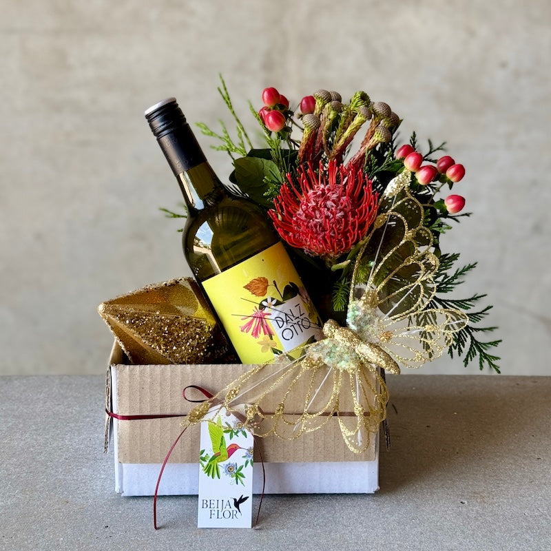 Christmas gift hamper with festive flowers, wine and gold ornaments