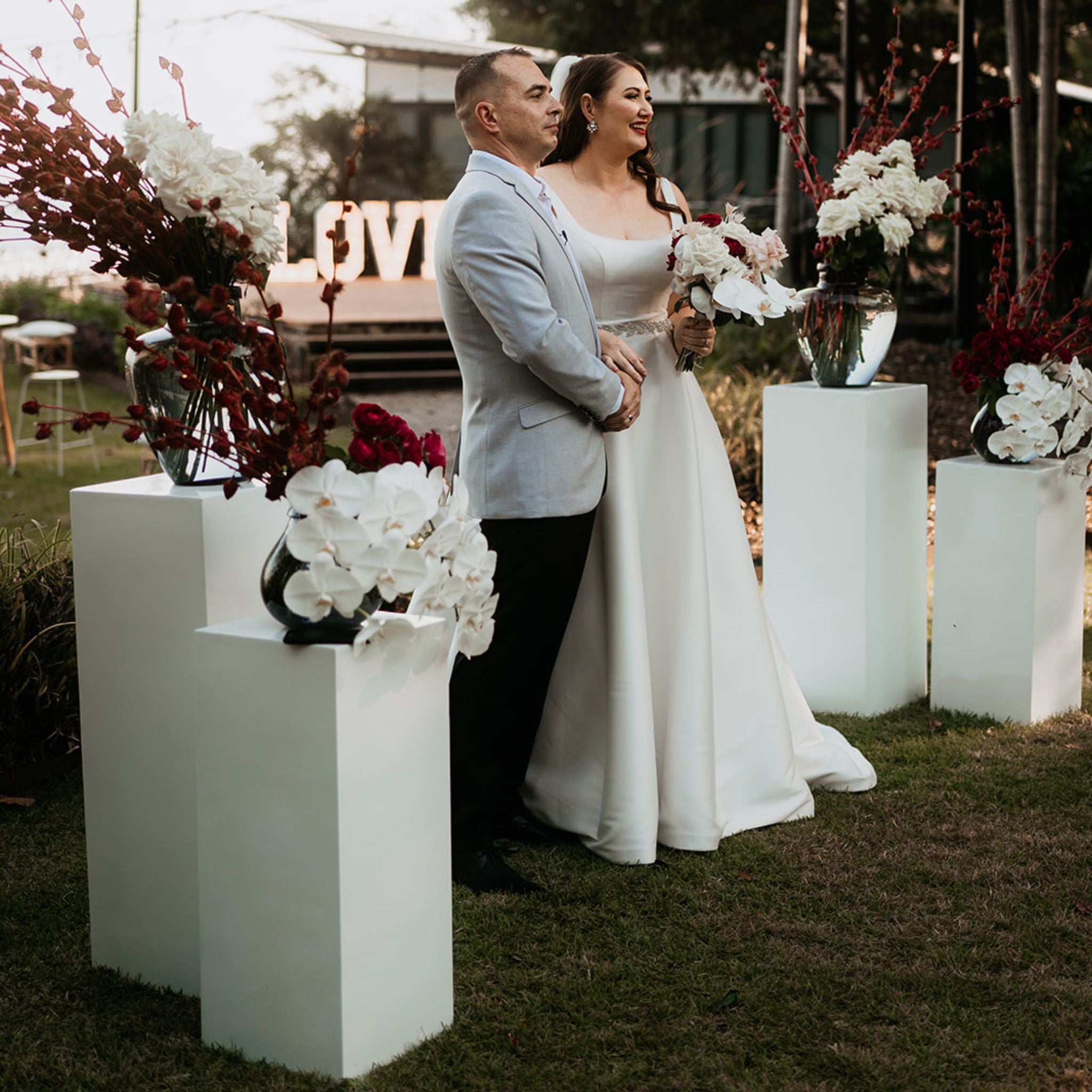 modern white plinth florals for a Darwin wedding ceremony striking tall red rosellas and white phalenopsis orchids to frame the bride and groom at Pee Wees at the Point