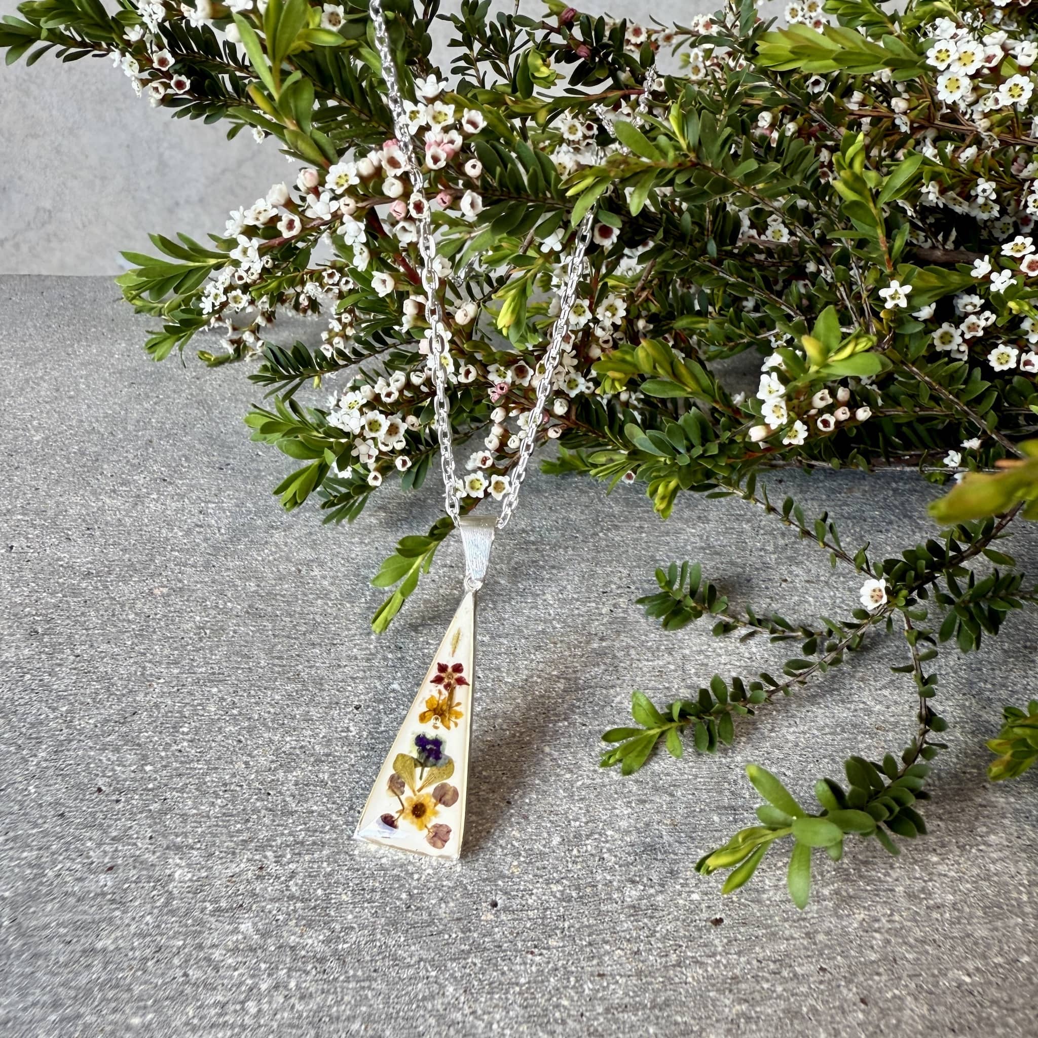 Wildflower Pendant with pressed miniature flowers in resin on a silver chain.