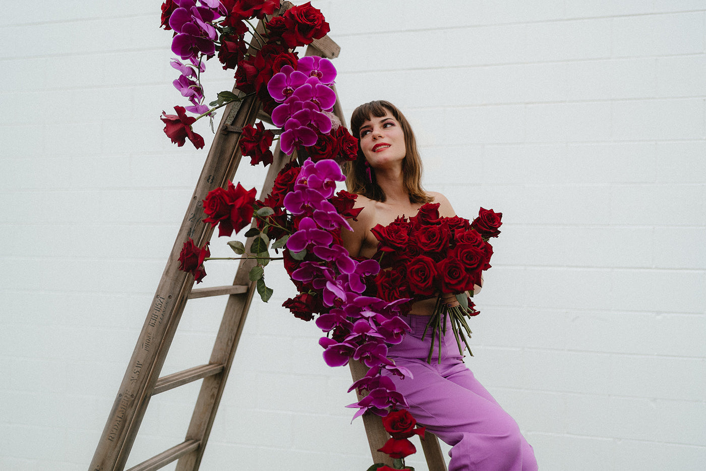 Girl holding bouquet of red roses and cerise orchids