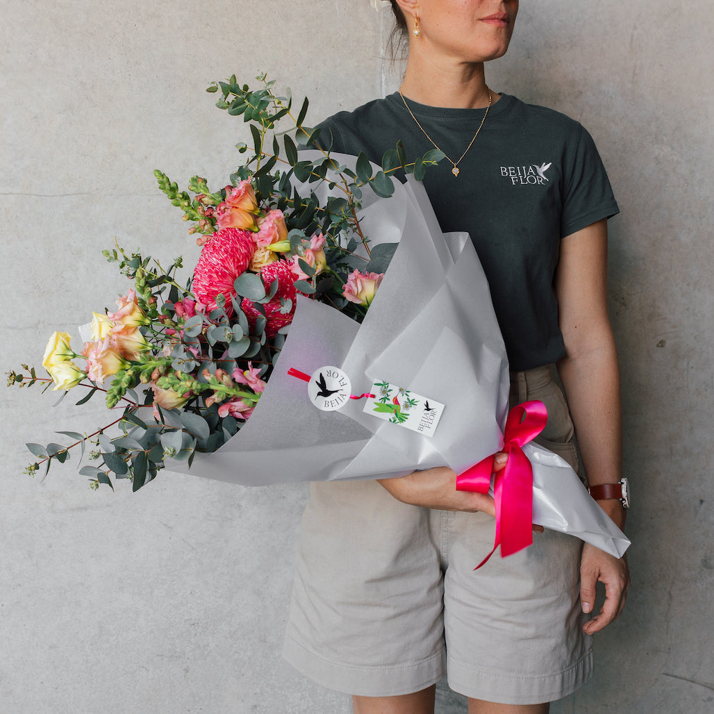 Bright pink blooms wrapped in white paper person holding
