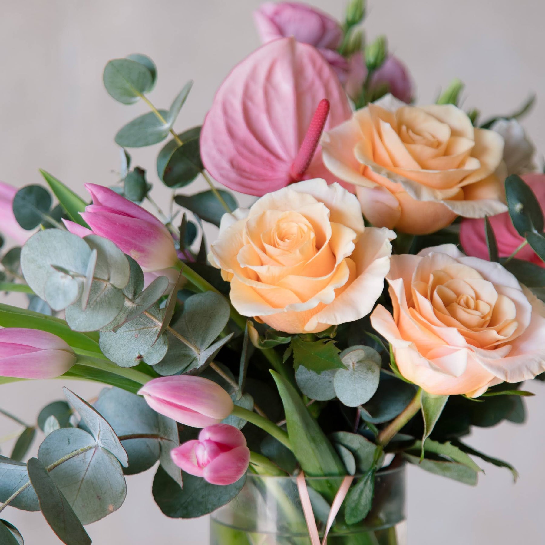 a bunch of Peachy toned flowers in a glass vase