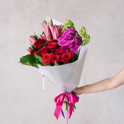 Valentines bouquet with one dozen roses alongside orchids and lilies. 