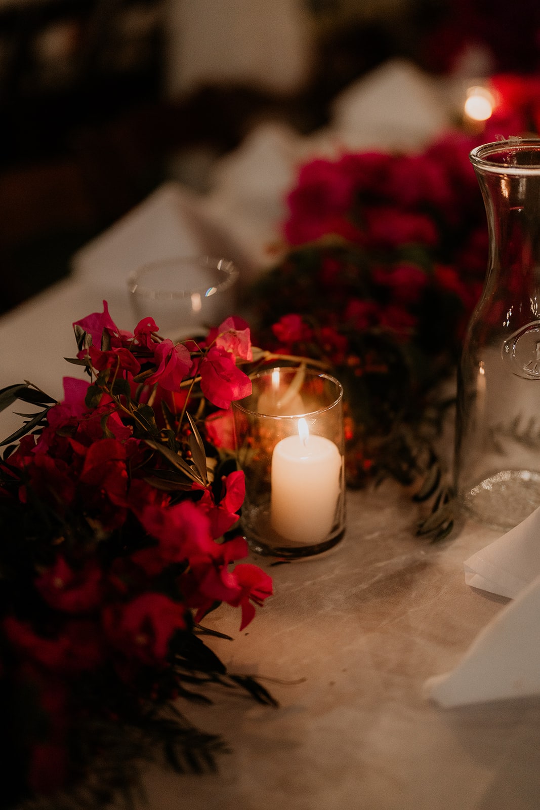 candle lit wedding reception tables with bougainvillea garland