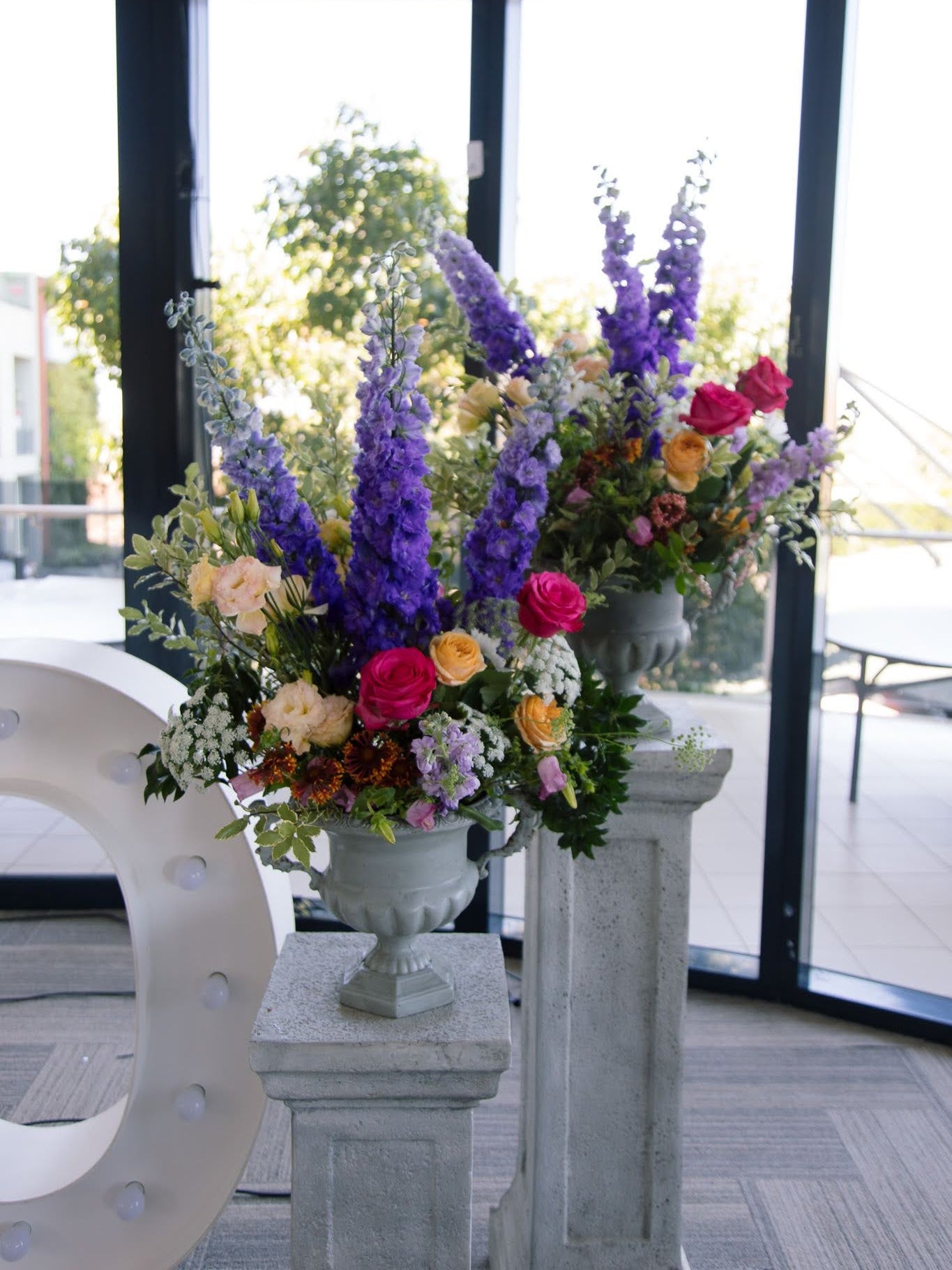 stone effect pillar with urn of colourful garden style flowers