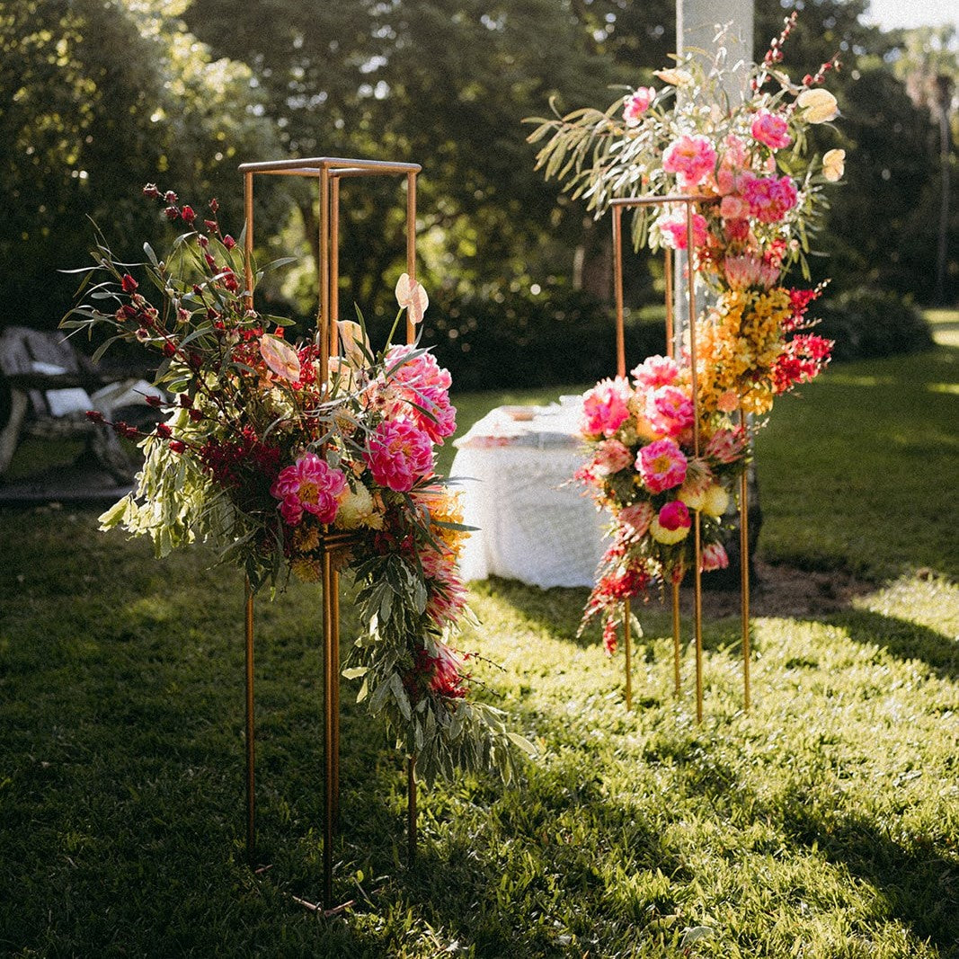 two geometric stands in burgundy theme covered with greenery by Beija flor