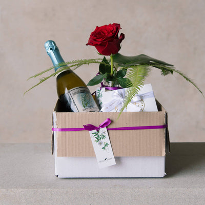 Valentines Day gift box with red rose, sparkling vine and chocolates