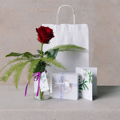 valentines day red rose in vase, with chocolates, greetings card and gift bag