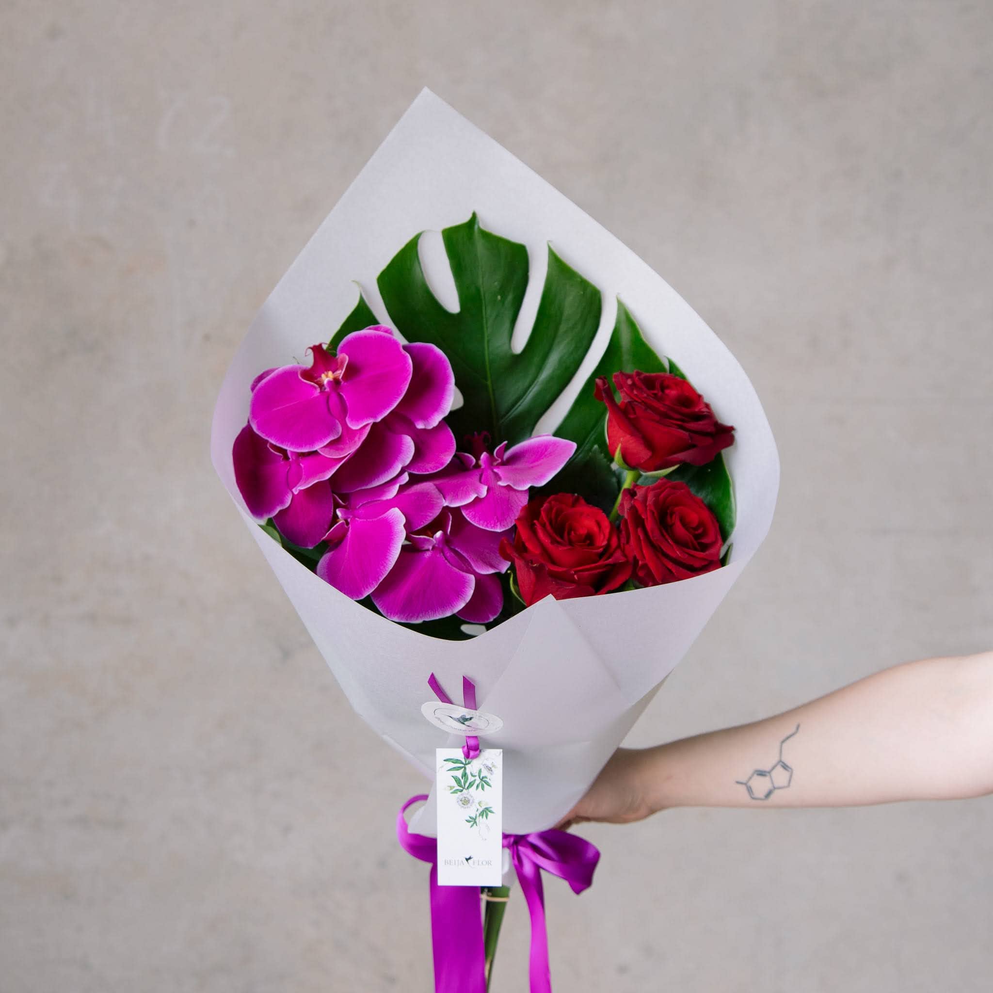 Valentines Day rose and phalenopsis orchid bouquet in white paper and ribbon. 